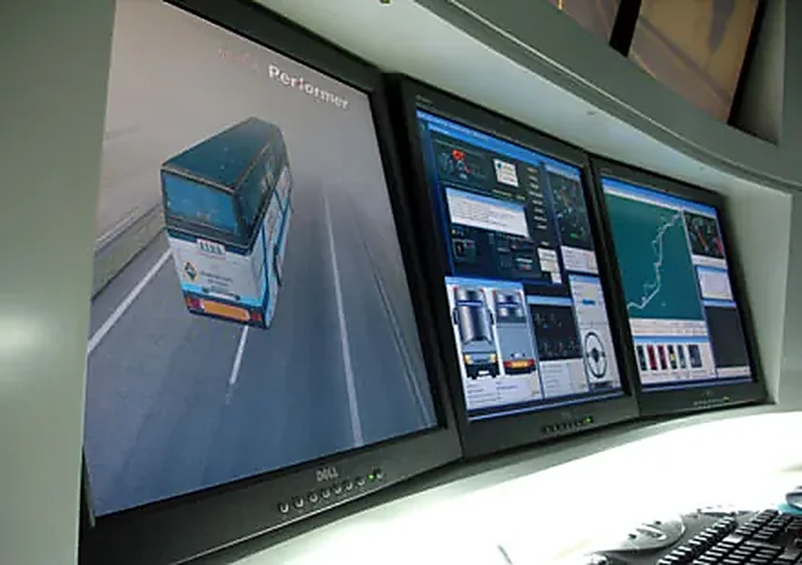 Puesto de instructor del simulador de autobús, con el vehículo en 3D y el trazado de la ruta repartidos en varias pantallas