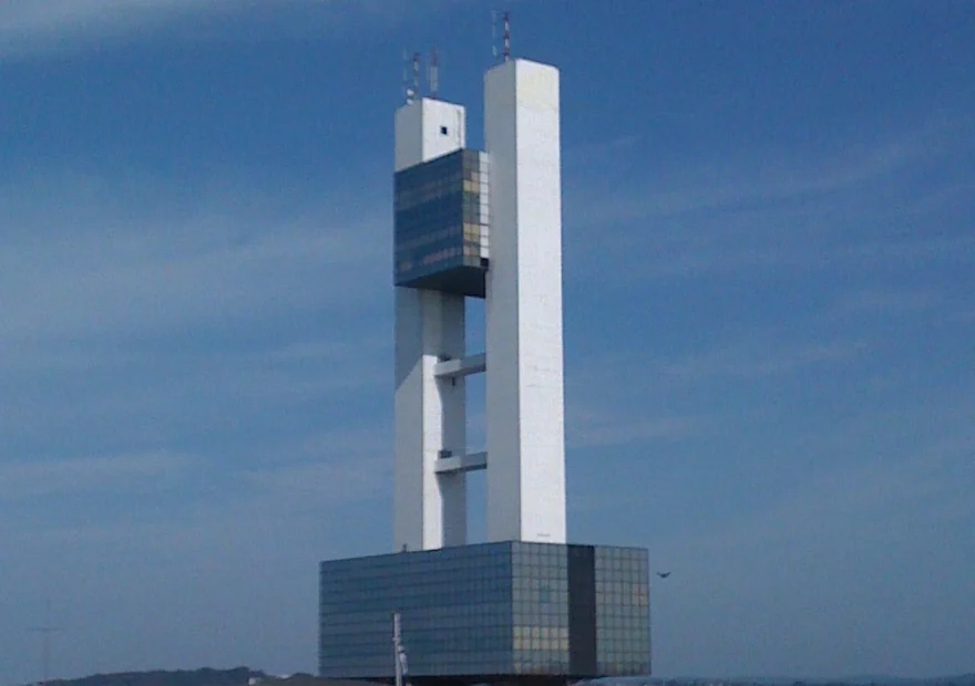 Torre de control de tráfico marítimo de un puerto, con su mirador acristalado recortado sobre el mar