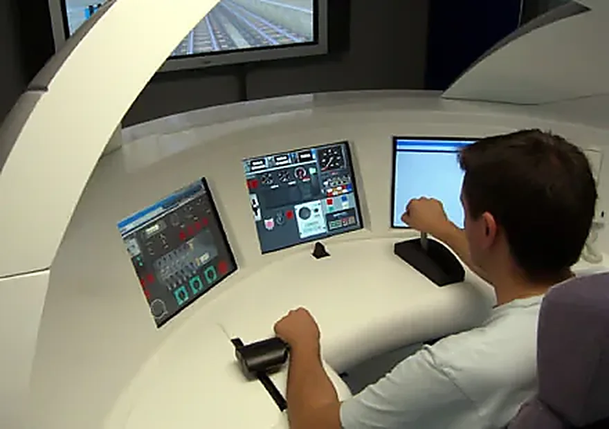 Alumno manejando los mandos de un simulador de conducción ferroviaria frente a las pantallas de vía
