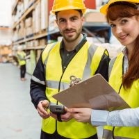 Warehouse team working together with clipboard in a large warehouse